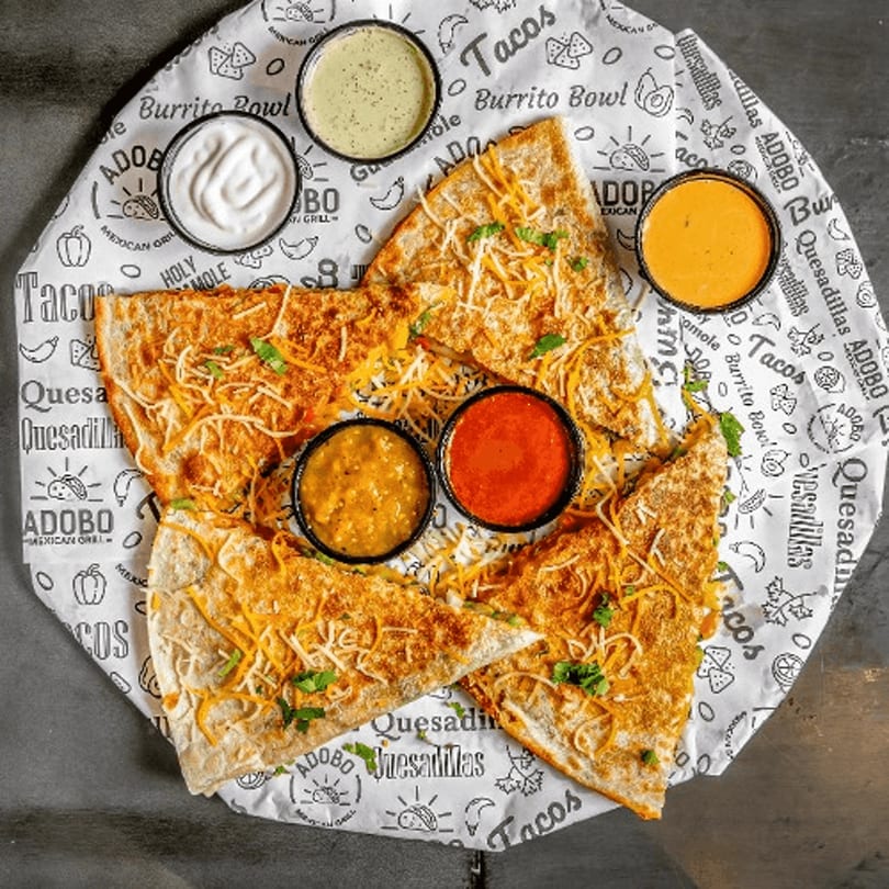 Four cheesy quesadilla slices with five dipping sauces on Taco Express branded paper.