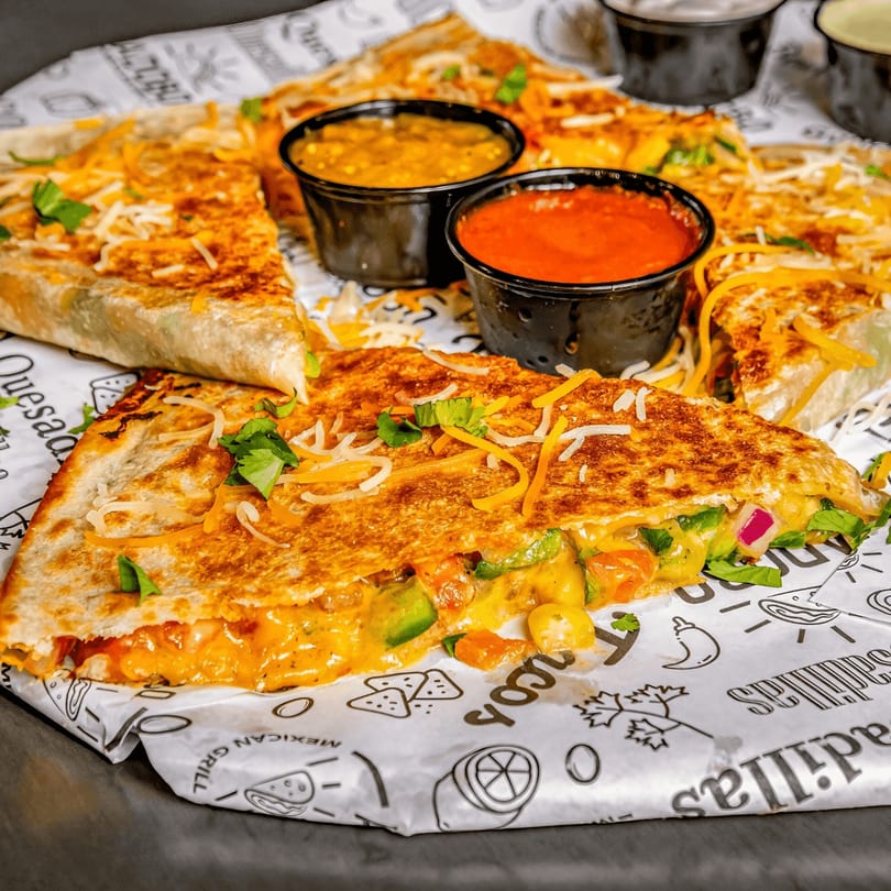 Cheesy quesadillas from Taco Express Mexican Grill, with salsa and cilantro on branded paper.